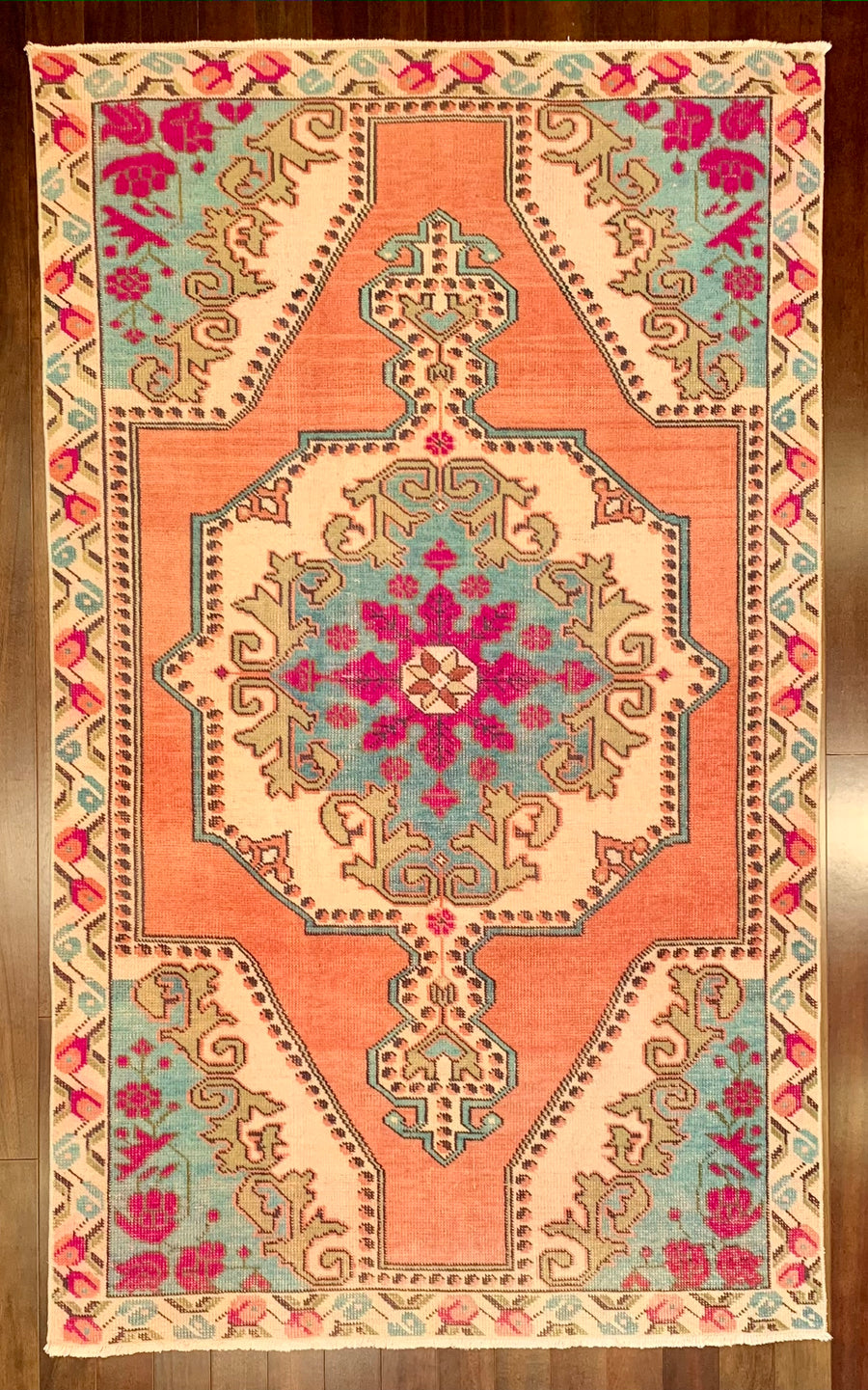 A traditional pattern wool area rug that has been over-dyed with bright orange, teal, magenta, and green for a modern look. 