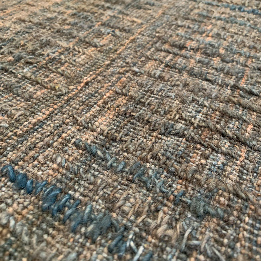 Close-up detail from the Storm in Cactus from the Avita Collection by Battilossi Rugs. This 6x9 hand-knotted rug features sea green, green, beige, and tan colors in 100% ghanzi wool